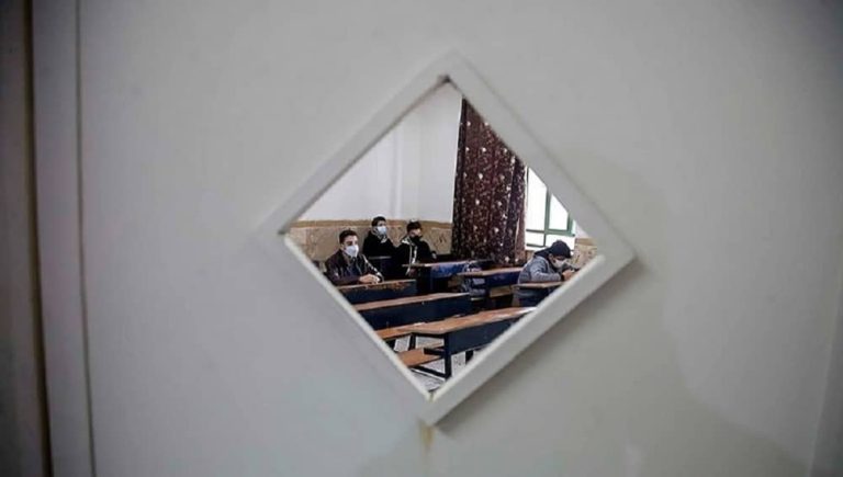 View into a boys' classroom in Iran through a small window in the door
