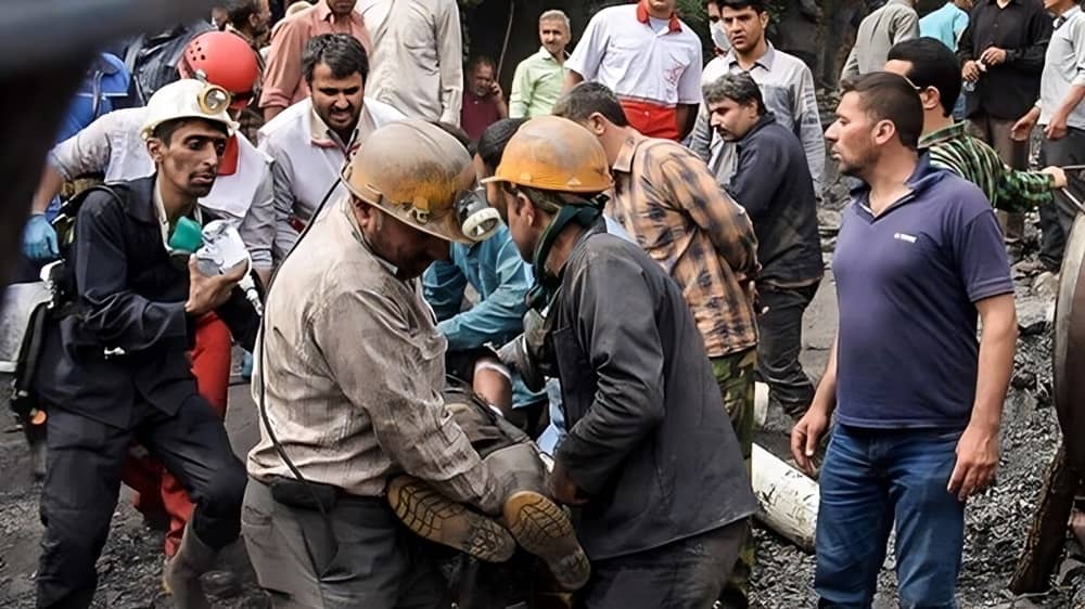 Iranian workers carry injured colleagues after a fatal mine accident