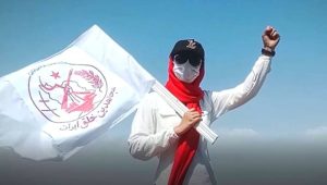 A female member of the MEK Resistance Units inside Iran raising the flag of the organization's emblem