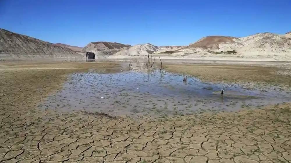 A nearly dry reservoir in Iran shows cracked earth and a shallow pool of stagnant water
