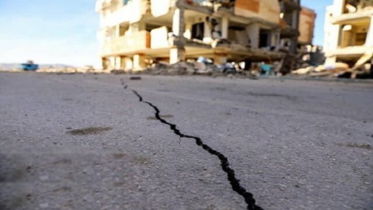 A deep crack cuts across a street beside a damaged building—an image of Iran’s mounting disaster risk and crumbling infrastructure.