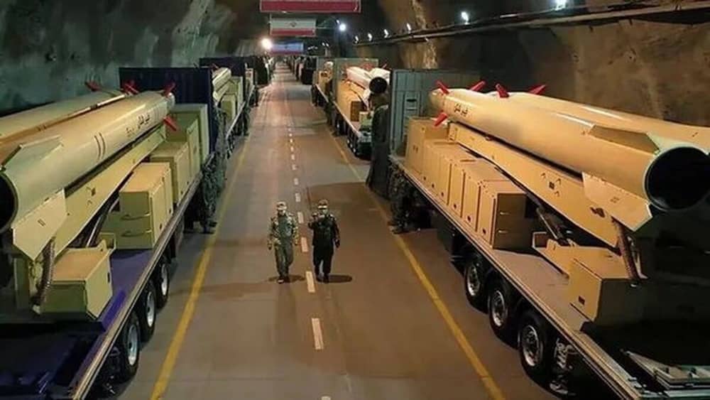 IRGC aero-space personnel walk past transporter-erector-launchers carrying ballistic missiles inside an underground tunnel facility