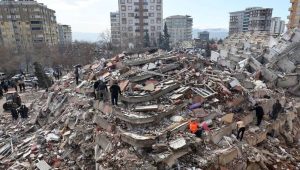 The aftermath of severe urban destruction following a major earthquake, where the collapse of a multi-story building into concrete rubble mirrors expert warnings that over 60 percent of the country's structures are unsafe