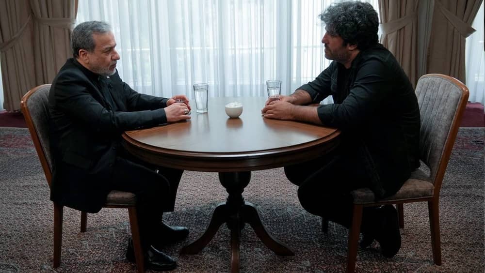 Iranian regime's Foreign Minister Abbas Araghchi (left) speaks with state security-aligned documentary film maker Javad Muguee during an interview on July 19, 2026