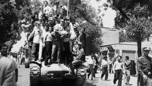 Crowds of pro-Shah mobs climb aboard and surround a military tank rolling through the tree-lined streets of Tehran on August 19, 1953, during the CIA- and MI6-backed coup d’état that overthrew Prime Minister Dr. Mohammad Mossadegh