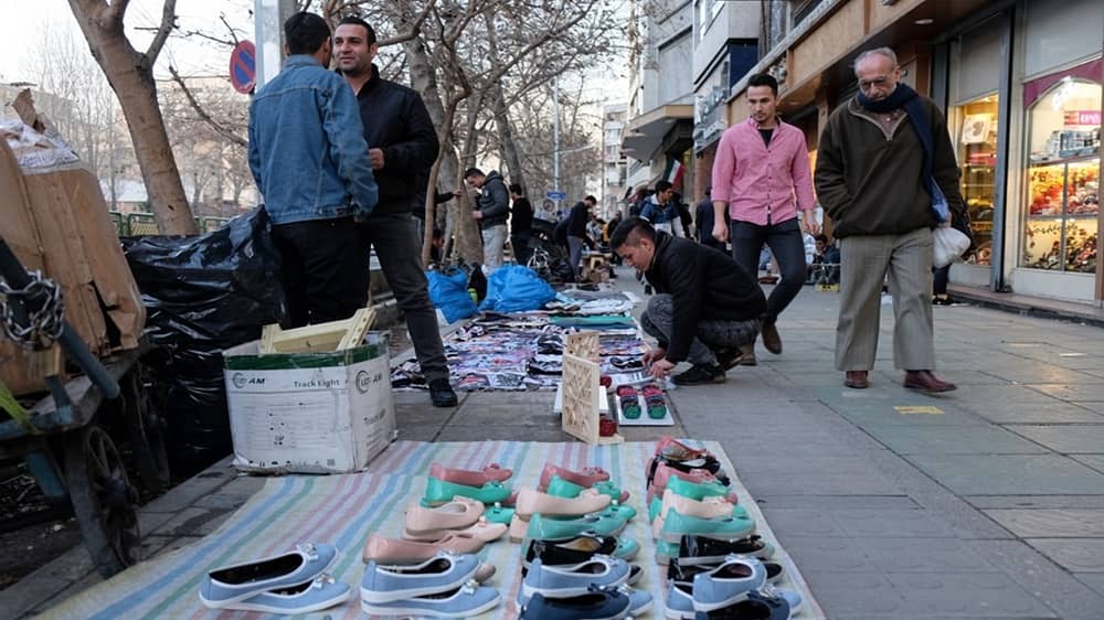 Street vendors display rows of women’s flat shoes on a striped blanket along the sidewalk of Zand Street in Shiraz, southern Iran
