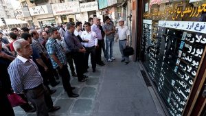 Crowds check dollar and euro rates at a Tehran currency exchange as Iran’s rial comes under pressure