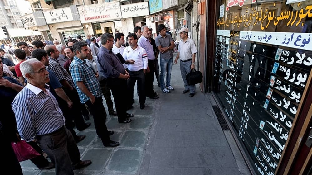 Crowds check dollar and euro rates at a Tehran currency exchange as Iran’s rial comes under pressure