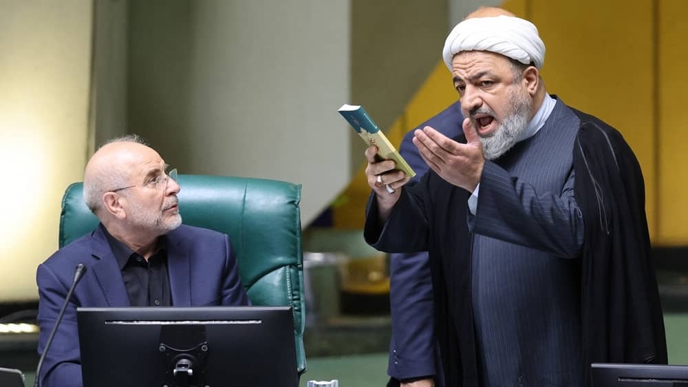 Iranian regime's Parliament Speaker Mohammad-Bagher Ghalibaf (left) stares at MP Hamid Rasaee (right) delivers a heated protest during a session of Majlis
